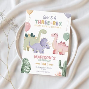 May include: A pastel-colored invitation card with the text "SHE'S A THREE-REX STOMP OVER TO CELEBRATE". The card features illustrations of three dinosaurs, balloons, and tropical plants. The text "MADISON'S 3RD BIRTHDAY" is also included, along with date, time, and address.