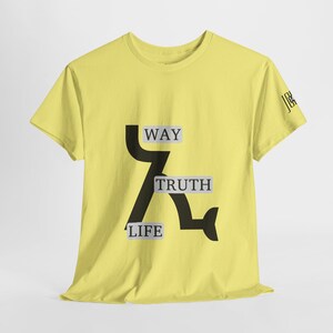 Puede incluir: Una camiseta amarilla clara con las palabras "WAY", "TRUTH" y "LIFE" en una fuente negra y estilizada. La camiseta también presenta un gráfico negro y las iniciales "JGK" en la manga.