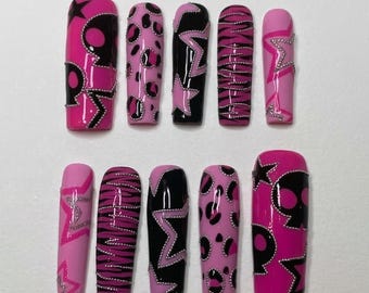 Op de afbeelding: Een set van tien lange, doodskistvormige persnagels. De nagels hebben verschillende ontwerpen, waaronder roze luipaardprint, zwart-roze sterpatronen en zebra strepen. Sommige nagels hebben zilveren versieringen.