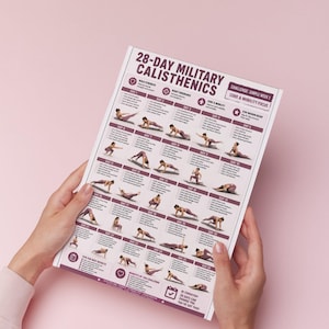 Op de afbeelding: Een fitnessschema getiteld "28-DAY MILITARY CALISTHENICS" wordt tegen een roze achtergrond gehouden. Het schema bevat een trainingsplan met oefeningen voor elke dag, inclusief illustraties en tekst. Het schema richt zich op core en mobiliteit.