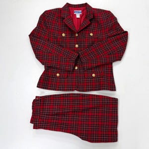 May include: A red and black plaid suit set, including a blazer and matching pants. The blazer has gold buttons and a red lining. The suit is a classic style, suitable for business or formal wear.