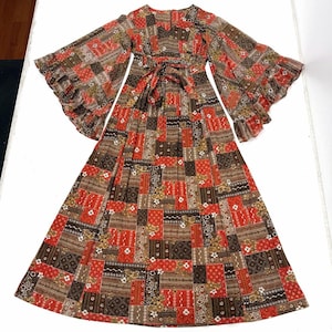 May include: A vintage patchwork maxi dress with long, flared sleeves and a matching tie belt. The dress features a V-neckline and a patchwork design in shades of red, brown, and cream. The sleeves have a ruffled hem.