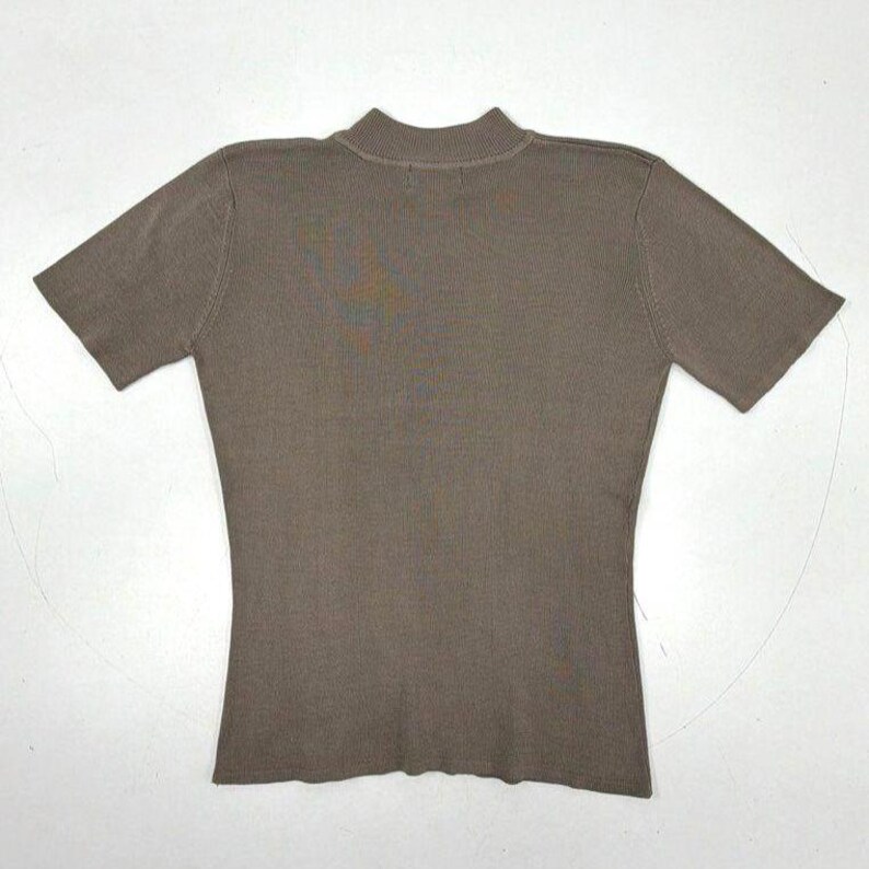 Op de afbeelding: Een effen taupekleurig shirt met korte mouwen en een opstaande kraag. Het kledingstuk is vervaardigd van fijngebreide stof met een gladde textuur, korte mouwen en een rechte zoom, wat zorgt voor een strak en eenvoudig ontwerp.