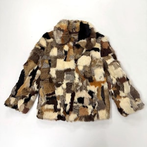 May include: A patchwork fur jacket in a variety of earth tones, including brown, beige, and black. The jacket has a collared neckline and long sleeves. The fur is arranged in a geometric pattern.