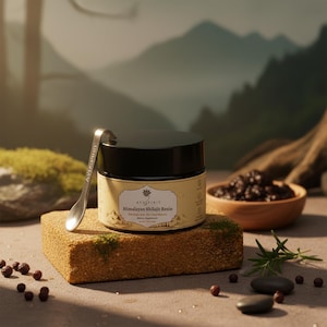 Puede incluir: Un frasco de resina de Shilajit del Himalaya con tapa negra y cuchara plateada. El frasco está sobre un bloque rectangular cubierto de musgo. Un pequeño cuenco de madera con resina oscura y una ramita de romero también están presentes.