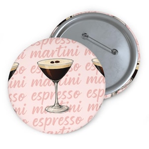 May include: A round button with an illustration of an espresso martini on a light pink background. The button has a metal pin back. The words "espresso martini" are repeated across the background.