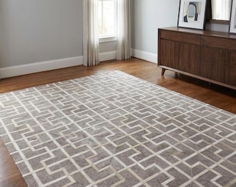 May include: A large rectangular area rug featuring a repeating geometric maze pattern in shades of gray and white. The rug is constructed from individual panels with a textured surface, displaying a consistent grid design across the entire piece.