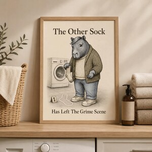 May include: A framed wall art print titled The Other Sock Has Left The Grime Scene, featuring a capybara wearing a cardigan, sweater, and jeans, standing next to a washing machine and a chalk outline of a sock with a number one evidence marker.
