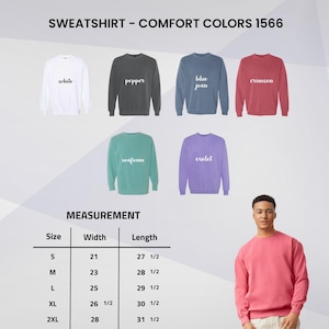 Puede incluir: Una selecci&oacute;n de sudaderas Comfort Colors 1566 en varios colores, incluyendo blanco, pimienta, azul vaquero, carmes&iacute;, espuma de mar y violeta. La imagen tambi&eacute;n muestra una tabla de tallas con medidas en cm. Una persona lleva una sudadera carmes&iacute;.
