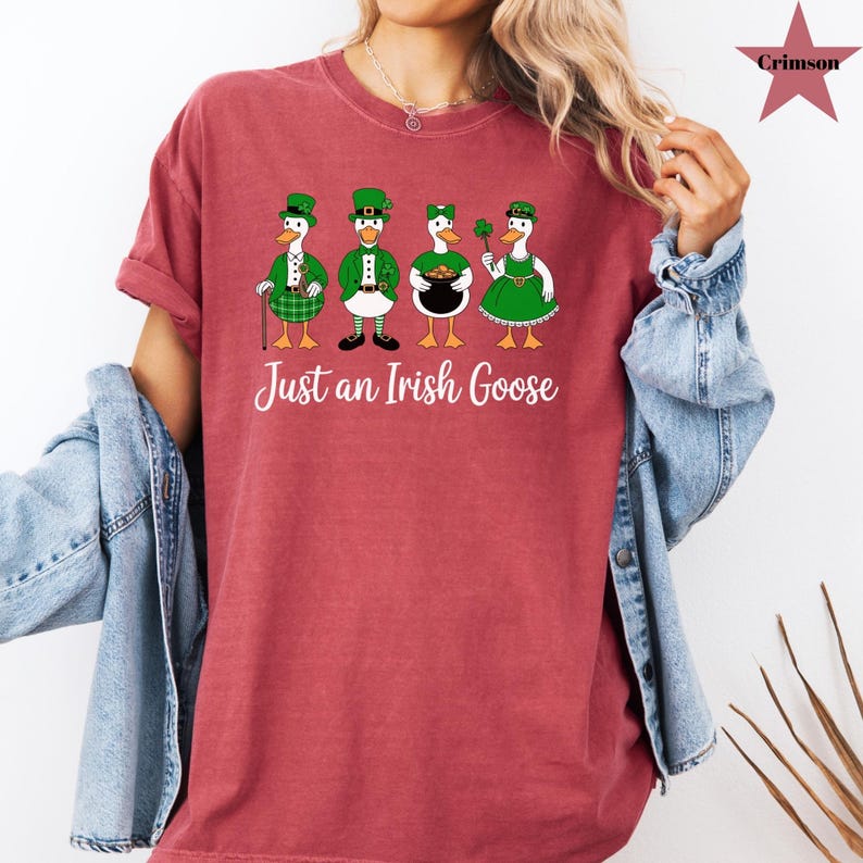 Puede incluir: Una camiseta granate con la frase "Just an Irish Goose". La camiseta muestra cuatro gansos de dibujos animados vestidos con atuendos del D&iacute;a de San Patricio: sombreros, chalecos y vestidos verdes. Un ganso sostiene una olla de oro.