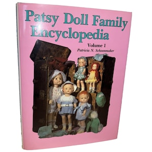 May include: A pink book cover with the title "Patsy Doll Family Encyclopedia" and images of vintage dolls. The cover features the text "Volume 1" and the author's name, Patricia N. Schoonmaker.