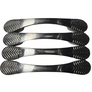 Op de afbeelding: Vier zilverkleurige kastgrepen. Elke greep is een gebogen staaf met een getextureerd, chevron-patroon uiteinde. De grepen zijn horizontaal gerangschikt, bovenop elkaar gestapeld. Het metaal heeft een licht verouderd uiterlijk.