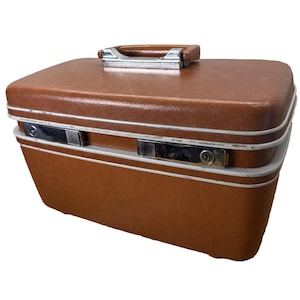 May include: A vintage brown suitcase with a rectangular shape. The suitcase has a handle on top and two silver latches on the front. A white stripe runs along the edges of the suitcase. The suitcase is made of a textured material.