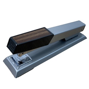 May include: A silver and black stapler with a wood grain top. The stapler has the text "Bates 500" on the front. The stapler is on a white background.