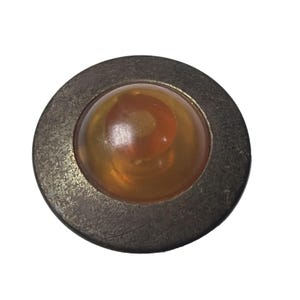 Könnte beinhalten: Ein runder Knopf im antiken Stil mit einem metallischen, strukturierten Außenring. Die Mitte hat einen klaren, bernsteinfarbenen, gewölbten Einsatz mit einem wirbelnden, rotbraunen Design. Der Knopf ist vor einem weißen Hintergrund platziert.