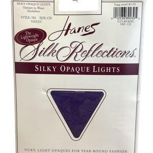 Peut inclure: Un emballage de bas Hanes Silk Reflections Silky Opaque Lights violets. L'emballage présente le nom de la marque et les détails du produit, y compris le style, la taille et un échantillon triangulaire de la couleur des bas. Le texte "Silky Opaque Lights" est bien visible.
