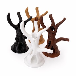 May include: Four tree-shaped stands in black, white, light brown, and dark brown. Each stand features a textured trunk with hollow openings and multiple upward-reaching branches, all supported by a circular base for stability on flat surfaces.