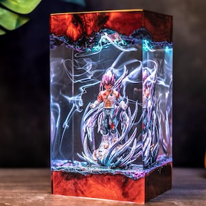 May include: A rectangular resin lamp featuring a dark reddish-brown wood base and top. Encased within the clear resin is a detailed anime character figure surrounded by swirling white smoke-like effects and sharp, blue-tinted energy spikes.