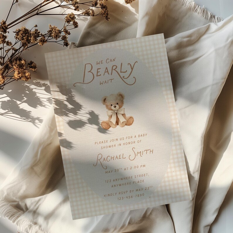May include: A rectangular baby shower invitation card featuring a light beige gingham pattern, a central illustration of a teddy bear with a cream ribbon, and the text WE CAN BEARLY WAIT, PLEASE JOIN US FOR A BABY SHOWER IN HONOR OF RACHAEL SMITH.