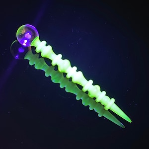 May include: A yellow glass dabber with a round, clear glass tip. The dabber is decorated with a series of raised bumps.