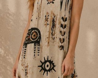 May include: A floor-length beige maxi dress featuring thin spaghetti straps and a V-neckline. The fabric is decorated with a repeating pattern of black and brown stylized deer, sunbursts, and geometric shapes across the entire garment surface.