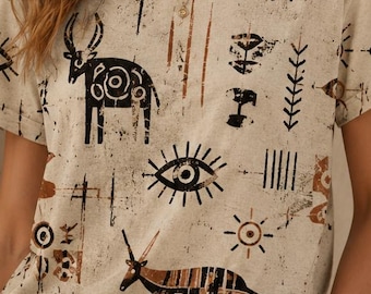 May include: Beige crew neck t-shirt with a tribal print featuring black and brown animal and eye illustrations. The short-sleeved shirt has a distressed look and is paired with beige pants.