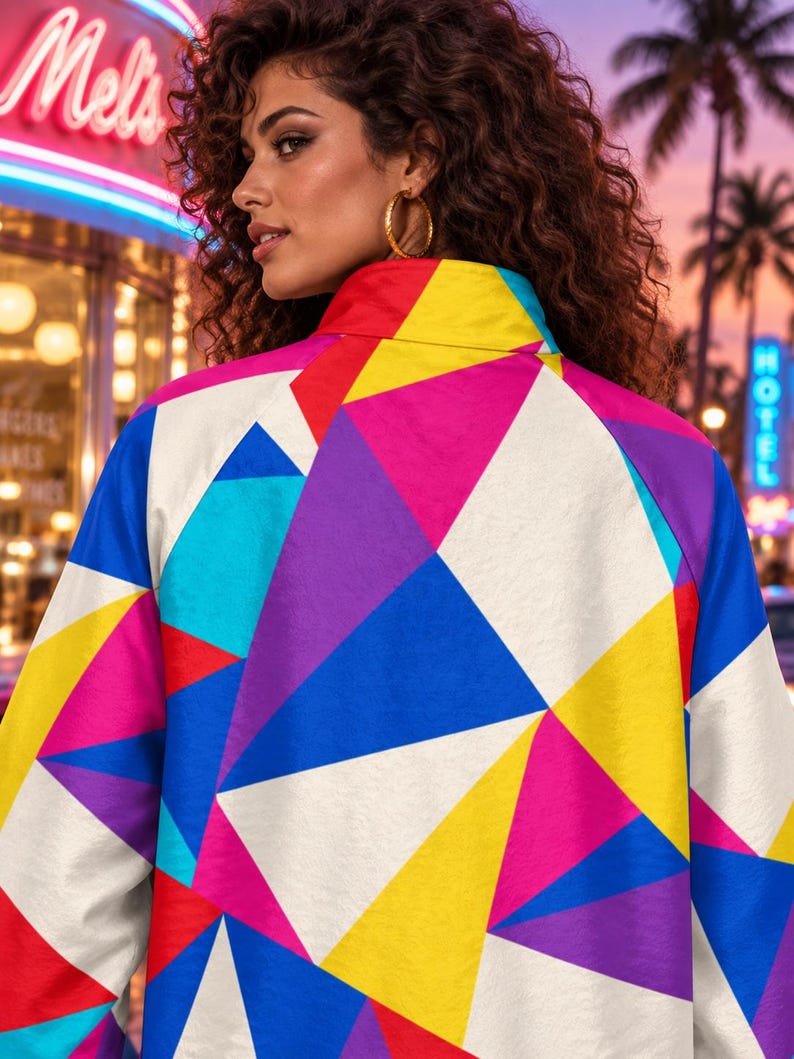 Puede incluir: Una chaqueta de cuello alto con un vibrante patr&oacute;n geom&eacute;trico de tri&aacute;ngulos en tonos amarillo brillante, azul real, magenta, morado y blanco. La prenda tiene mangas largas y un corte estructurado que muestra un dise&ntilde;o abstracto multicolor y llamativo.