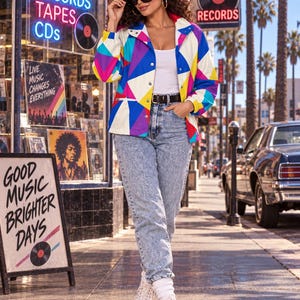 Puede incluir: Una chaqueta de manga larga con un vibrante patr&oacute;n geom&eacute;trico en tonos azul, amarillo, rosa y blanco, usada sobre una camiseta sin mangas blanca con jeans azules de lavado &aacute;cido, un cintur&oacute;n negro y zapatillas blancas de ca&ntilde;a alta.