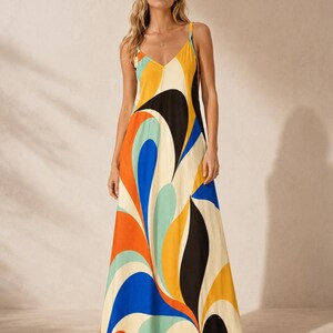 May include: A floor-length maxi dress featuring a vibrant, abstract swirl pattern in shades of orange, blue, yellow, black, and cream. The garment has a V-neckline, thin spaghetti straps, and a relaxed, flowing silhouette that reaches the floor.