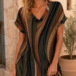 Può includere: Un abito a maniche corte con scollo a V e un audace motivo astratto di linee verticali fluide in tonalità verde oliva, marrone scuro, nero e beige. Il capo presenta una vestibilità rilassata con maniche con risvolto e orlo dritto.