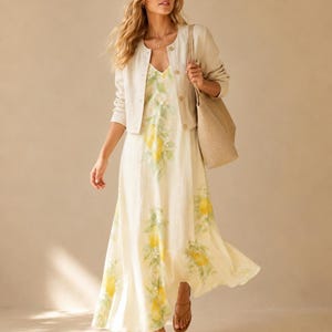 A woman in a lemon-print maxi dress and a cream cardigan carries a large woven tote bag.