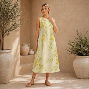 May include: A sleeveless midi dress in a pale yellow hue, featuring a repeating pattern of bright yellow lemons and green leafy branches. The dress has a round neckline and a straight, relaxed silhouette that falls below the knees.