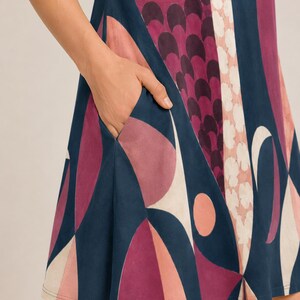 May include: A sleeveless dress featuring a bold geometric pattern in shades of deep navy blue, magenta, and soft pink. The garment includes a functional side pocket integrated into the seam, showcasing a repeating abstract design of circles and arcs.