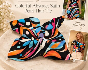 May include: A satin hair tie featuring a black background with a colorful abstract pattern of orange, blue, and pink shapes. The hair tie has two white pearl accents at the ends. The text on the image reads Complete the Look, Colorful Abstract Satin Pearl Hair Tie, Same Print Story, and Designed in the same print story as our matching collection pieces. Style it on its own or pair it with coordinating apparel for a complete look. Matching garments sold separately.