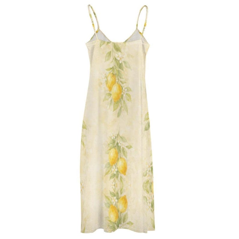 The back of a light yellow spaghetti strap maxi dress with a lemon and leaf print hangs on a wooden hanger.