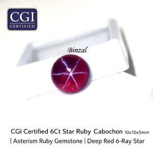 Könnte beinhalten: Ein tiefroter Sternrubin-Edelstein mit einem sechsstrahligen Sternmuster. Der Cabochon misst 10x10x5mm und ist CGI-zertifiziert. Das Bild enthält auch den Text "Binzal" und "CGI CERTIFIED".
