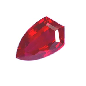 Op de afbeelding: Een gefacetteerde, rode edelsteen met een unieke, langwerpige vorm. De edelsteen heeft een hoge mate van helderheid en reflecteert licht om een briljante uitstraling te creëren. De slijpvorm heeft een platte bovenkant en een gebogen onderkant.