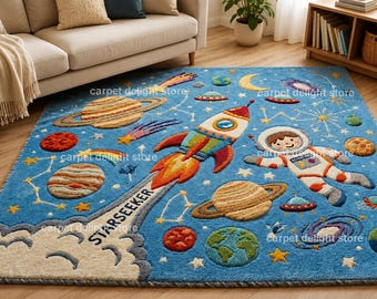 May include: A rectangular blue area rug featuring a space theme with a central rocket ship, an astronaut, planets, stars, and galaxies. The rocket ship has a trail of smoke with the text STARSEEKER printed on it. The design includes colorful celestial bodies.