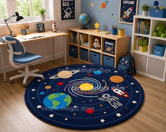 May include: A circular area rug featuring a deep blue background with a vibrant solar system design. The rug displays colorful planets, a central swirling galaxy, a white astronaut figure, a rocket ship, and scattered white stars across the surface.