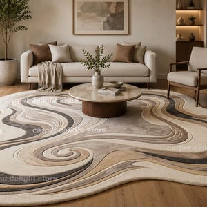 Könnte beinhalten: Abstrakter Teppich mit fließendem Design in Beige-, Braun- und Grautönen. Der Teppich befindet sich in einem Wohnzimmer mit Sofa, Sessel und Couchtisch. Die ungefähren Abmessungen des Teppichs betragen 244 cm x 305 cm.