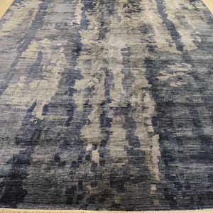Puede incluir: Una alfombra rectangular con un patr&oacute;n abstracto de tonos mezclados en azul marino, gris pizarra y blanco roto. El dise&ntilde;o consiste en variaciones de color verticales y veteadas con una apariencia tejida y un fleco corto en el borde.