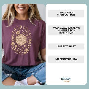 May include: A maroon unisex t-shirt featuring a gold floral and geometric design. The shirt has short sleeves and is made of 100% ring-spun cotton. The text on the shirt reads "Unisex T-Shirt" and "Made in the USA".