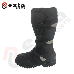 May include: Black motorcycle boot with silver buckles and a robust sole. The boot features a tall shaft and reinforced sections for protection. The "exta SPORTS" logo is visible in the upper left corner.