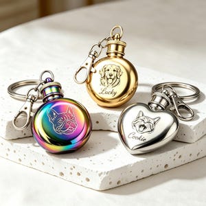 May include: Three pet memorial keyrings. One is gold with a dog portrait and the name "Lucky". Another is rainbow-coloured with a French bulldog portrait. The third is heart-shaped, silver, with a cat portrait and the name "Cookie".
