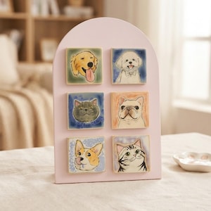 Op de afbeelding: Een lichtroze boogvormige displaystandaard met zes vierkante tegels met handgeschilderde illustraties van dieren. De tegels tonen een golden retriever, een witte hond met een vlinderdas, een grijze kat, een Franse bulldog, een corgi en een cyperse kat.