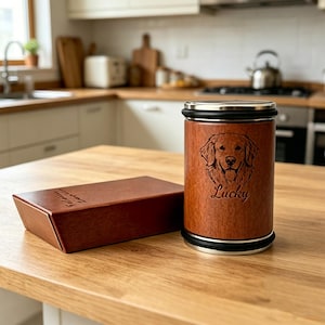 Pode incluir: Uma urna de madeira para animais de estimação com aro e base de aço inoxidável, apresentando uma imagem gravada de um Golden Retriever e o nome "Lucky". Uma caixa marrom combinando está ao lado da urna. A urna está em uma mesa de madeira.