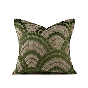 May include: A square throw pillow featuring a textured, velvet-like fabric in shades of olive green and muted taupe. The surface displays a repeating, fan-shaped pattern composed of layered, rounded petal motifs that create a dimensional effect.