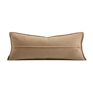 May include: A rectangular cushion in a neutral beige hue. It features a darker brown trim and a horizontal seam. This decorative cushion is designed for home decor and measures approximately 60 cm in length.