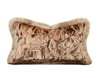 May include: A rectangular decorative pillow with a brown and tan floral pattern on a velvet-like fabric. The pillow is trimmed with a fringe border in a lighter brown color. The pillow is designed for home decor.