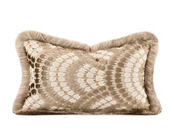 May include: A rectangular decorative pillow with a beige snakeskin pattern and a fringe border. The pillow's pattern features a repeating design of white and brown teardrop shapes. The fringe is a light brown color.